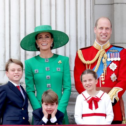 Princess Kate wears a green hat and matching outfit and stands on the Buckingham Palace balcony with Prince George, Princess Charlotte, Prince Louis, and Prince William