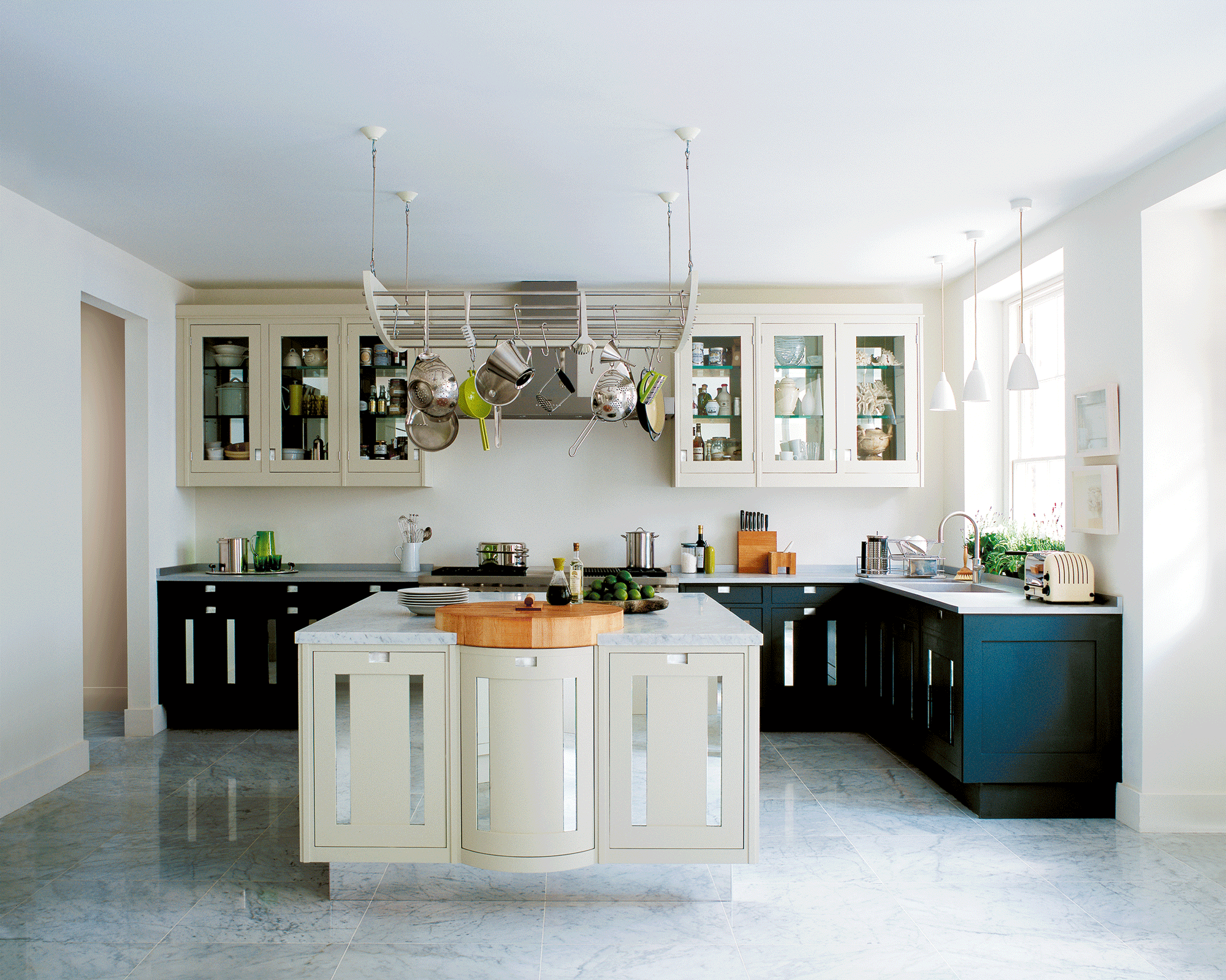 Off-white and black kitchen with hanging rack above the island