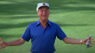 Rodney Dangerfield in a blue shirt and white hat, holding his arms out with an excited look on his face in Caddyshack.