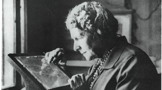 black-and-white photo of an older woman examining a photographic plate