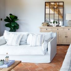 A bright open-plan living room with a white sofa positioned away from walls