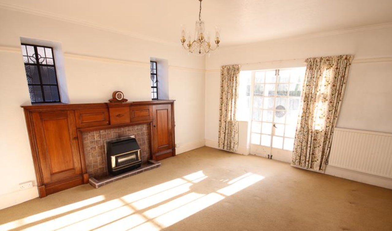 Living room with olden styled fireplace lit by natural light from large window