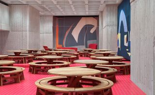 Wooden circular seats fill a room with a red carpet
