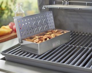 A stainless steel smoker box on a weber gas grill