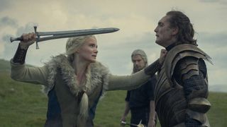 (L to R) Freya Allan as Ciri, Henry Cavill as Geralt and Eamon Farren as Cahir, with Ciri holding a blade at Cahir as Geralt watches, in The Witcher season 4