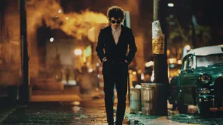 Timothée Chalamet as bob dylan wearing a black suit walking down a new york city street in 'A Complete Unknown'