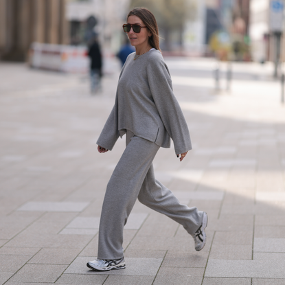 Elise Seitz seen wearing brown vintage aviator sunglasses, gold necklace, Soho Studios light grey wool knit sweater, matching Soho Studios light grey wool knit jogger pants and ASICS white / silver sneakers, on April 20, 2024 in Hamburg, Germany. 