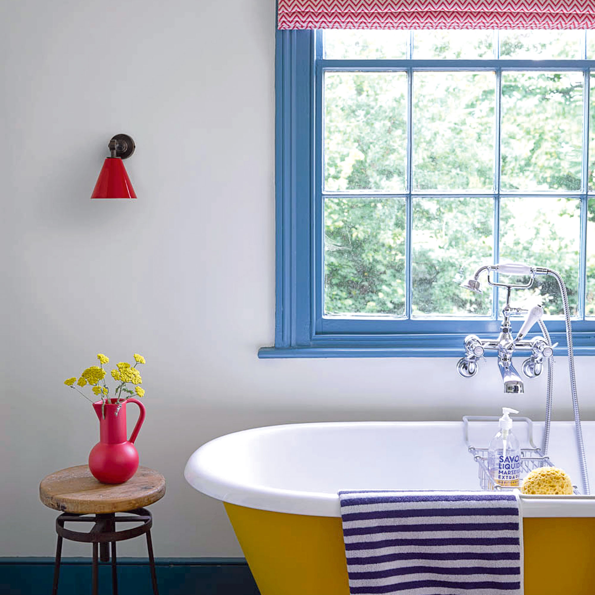 White bathroom with yellow bathtub, red lamp and blue painted window frame