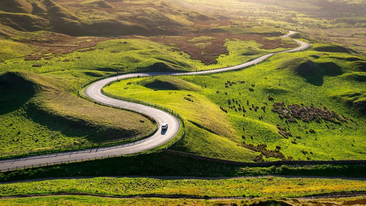 Car driving in the hills of England on a sunny evening representing the best road trips in the uk