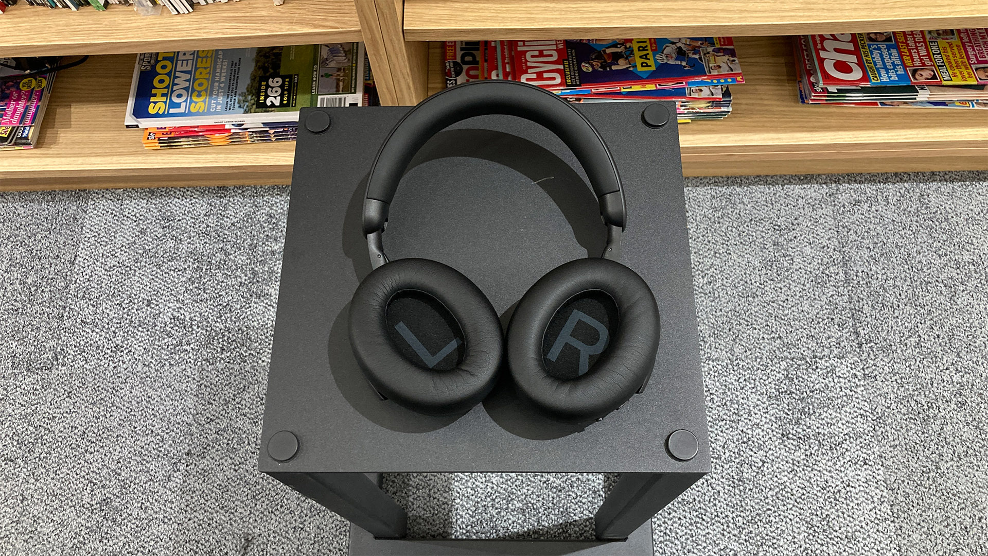 Philips TAH8000E wireless over-ear headphones on black table in front of bookcase