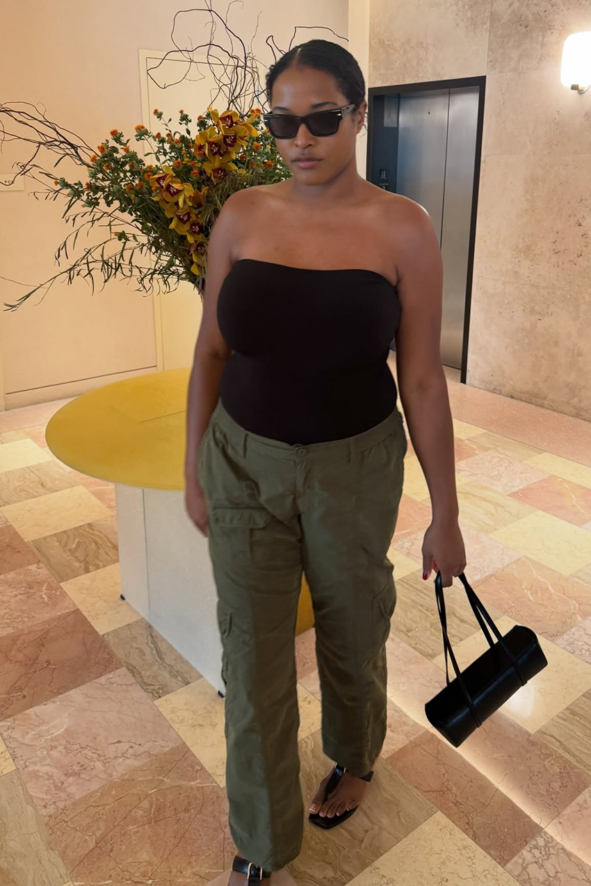 A woman wearing a black tube top, green cargo pants, and black sandals.