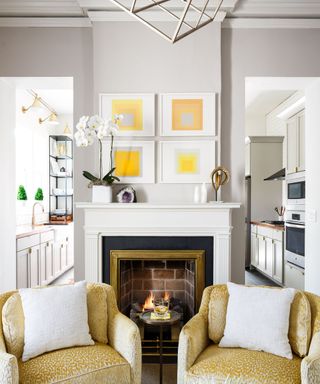 neutral living room with fireplace, yellow artwork and two yellow armchairs