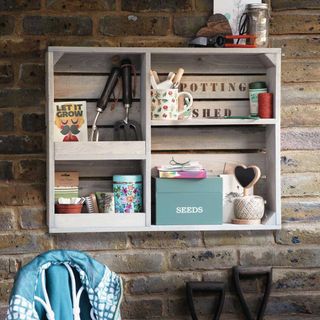 white wall shelf on brick wall with gardening tools