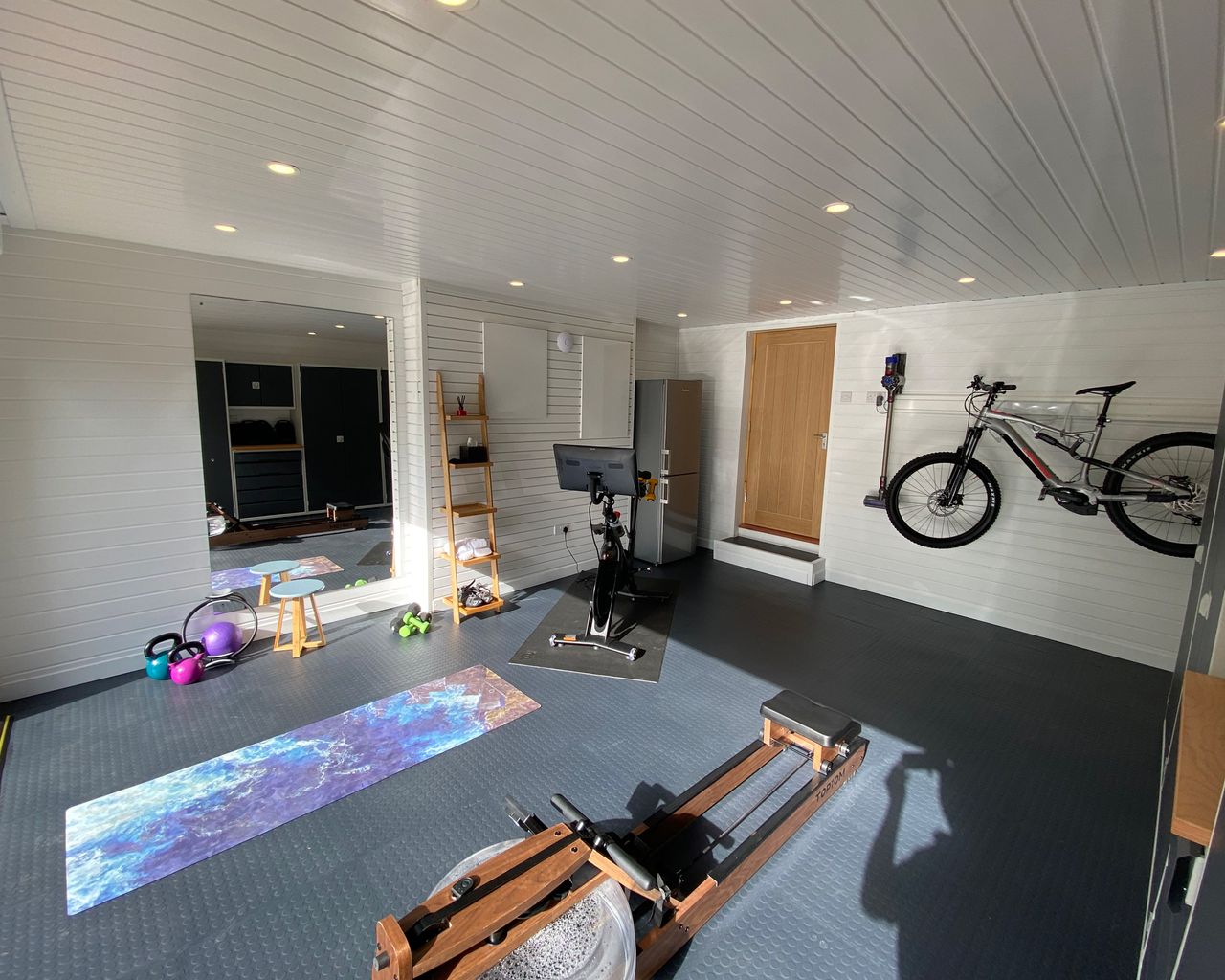 Home gym in the garage with yoga mats and bike on the wall