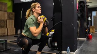 Woman performs goblet squat in gym with kettlebell