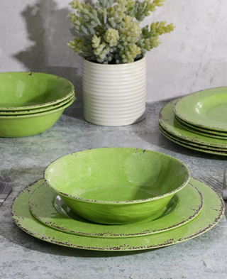 three stacks of green plates on a table with a vase and flowers