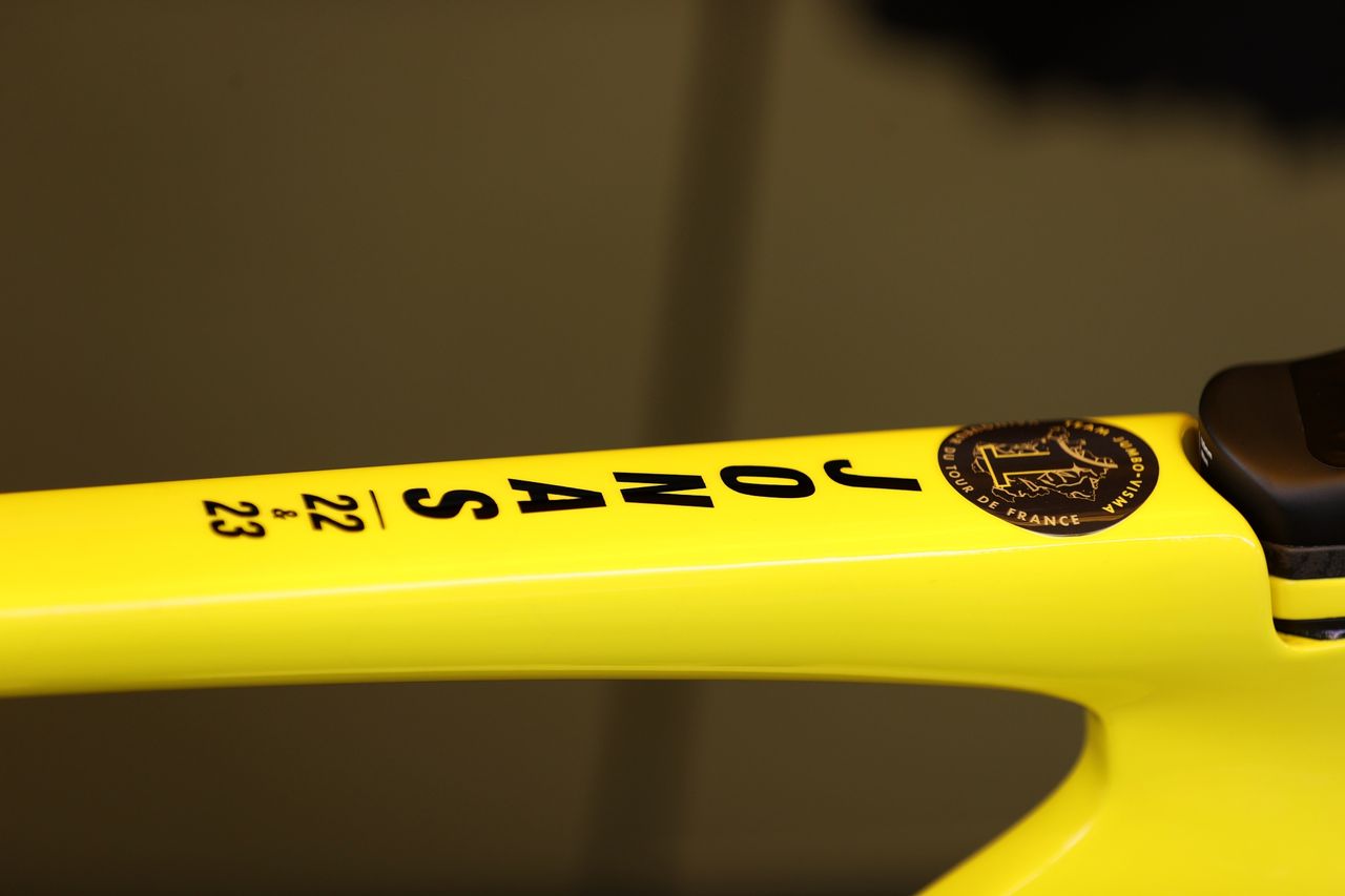 Jonas vingegaard on the podium at the tour de france 2023 holding his winning bike in the air