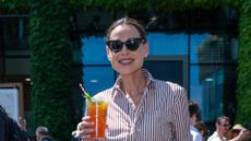Minnie Driver in a striped shirt, holding some Pimms