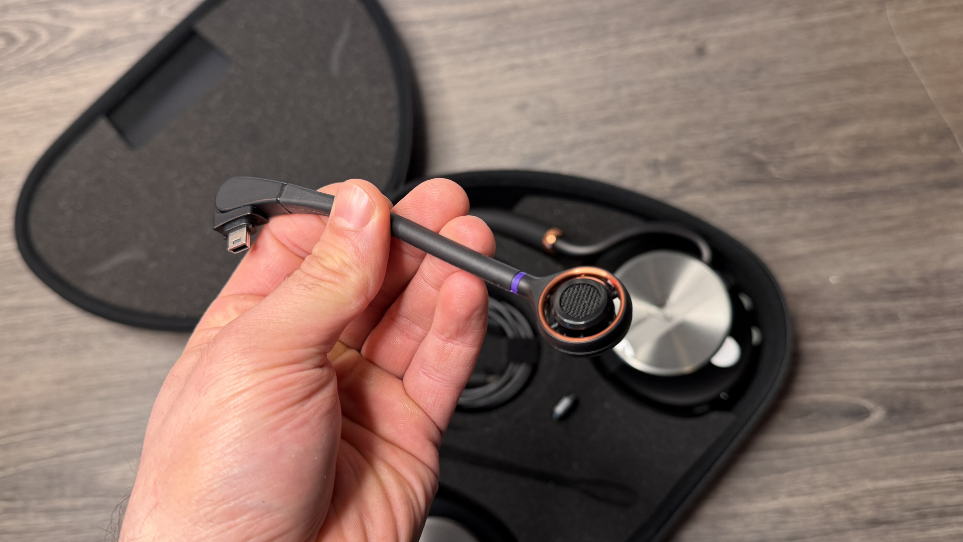 A man holding the microphone of the Turtle Beach Stealth Pro 2 headset above the headset sitting in its carry case below.