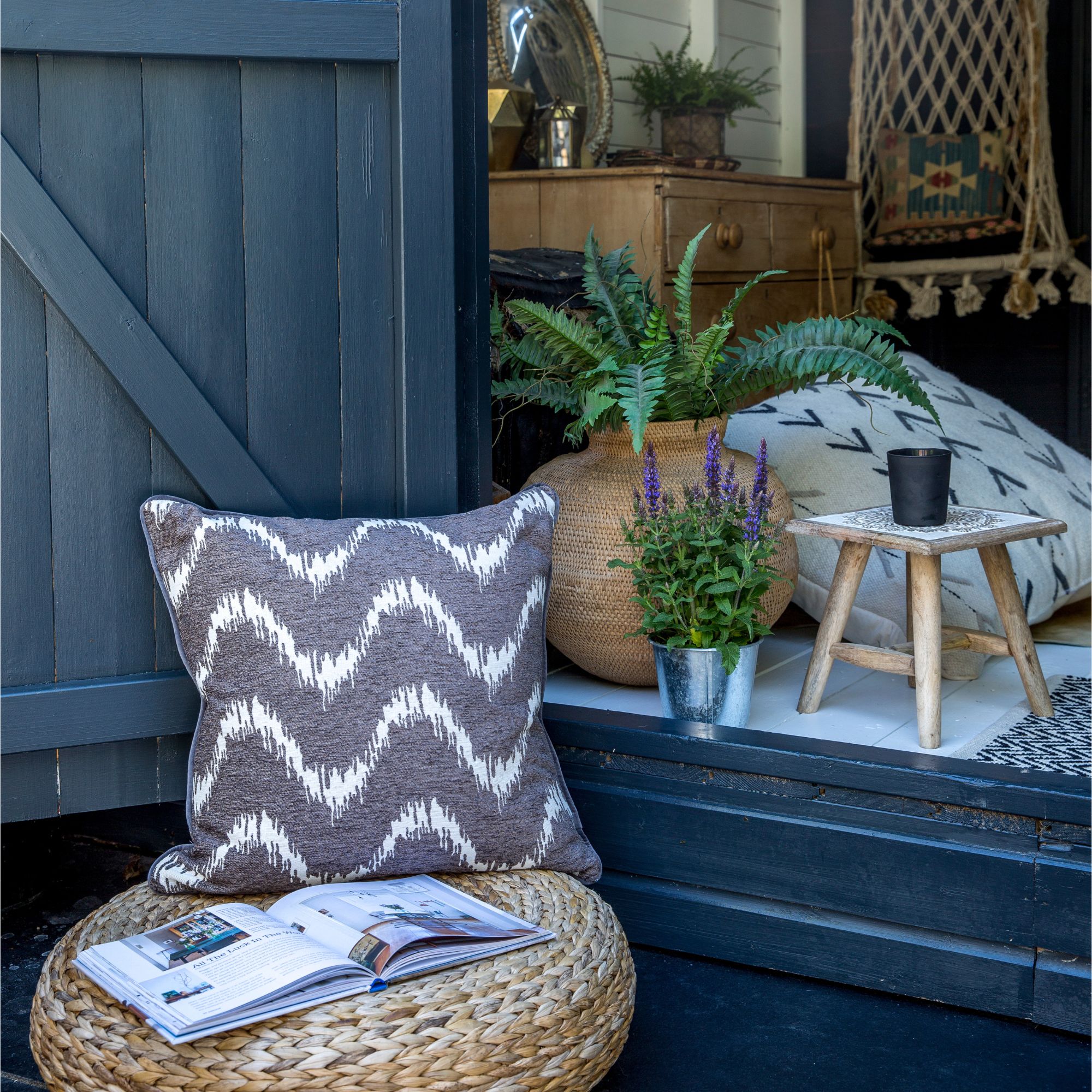 A garden shed with an outdoor seating area outside layered with potted plants