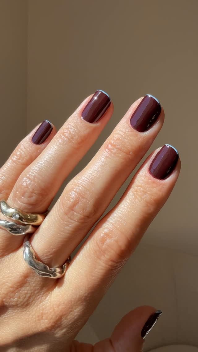 A dark red manicure with contrast light blue French tips