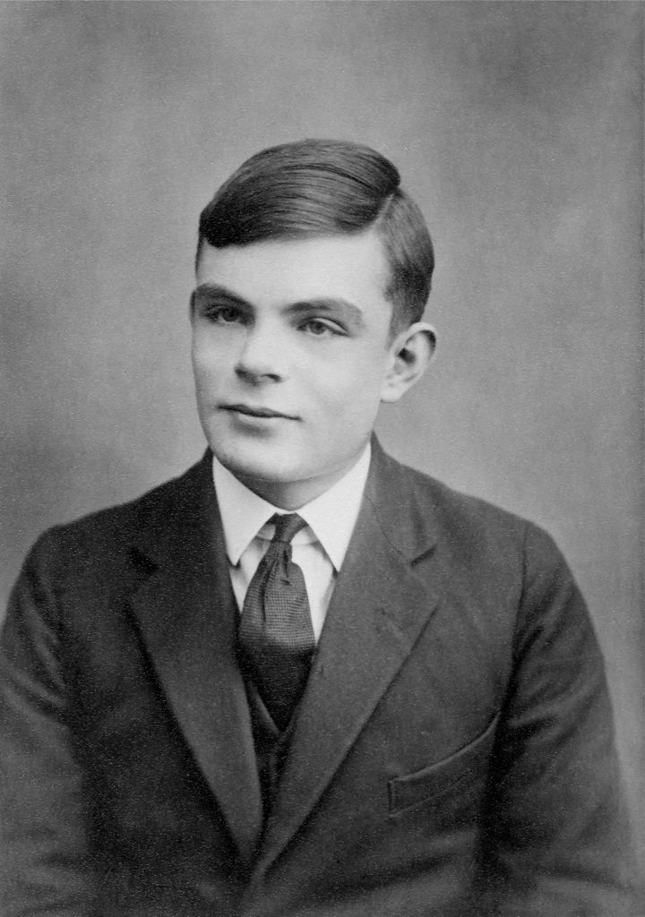 A black and white photo of a young man wearing a suit and tie looking to the left of the camera
