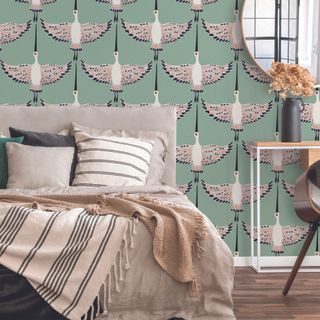 Bright mint green crane wallpaper behind bohemian bed decor with throws and cushions