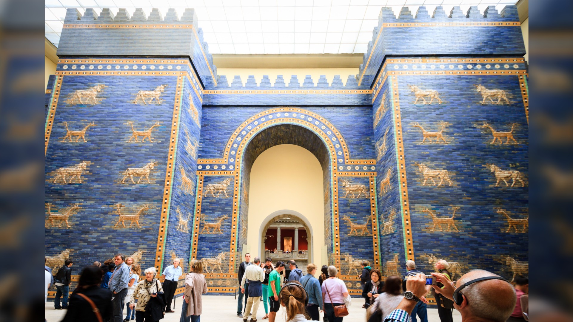 Reconstructed Ishtar Gate from Babylon in the Pergamom Museum, Berlin, Germany. It is a very tall structure made out of blue bricks and has golden horses on it.