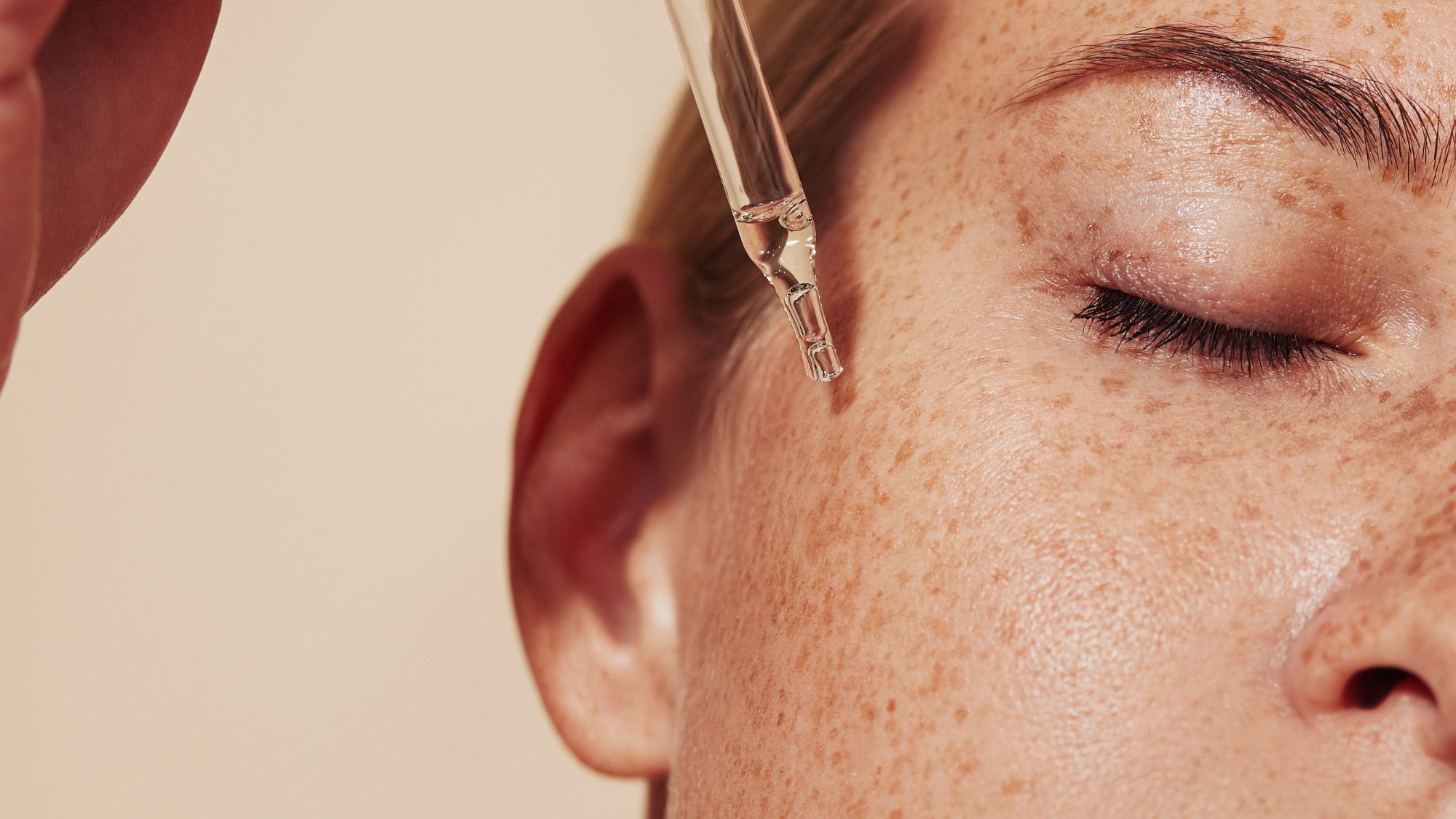 woman applying face serum with a pipette