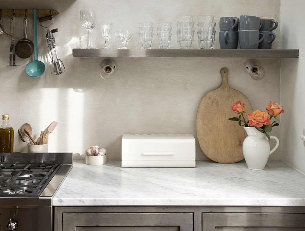 kitchen counter with wood chopping board and mugs on open shelving