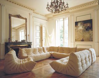 A living room drenched in yellow tones with several beige Togo sofas placed on the floor