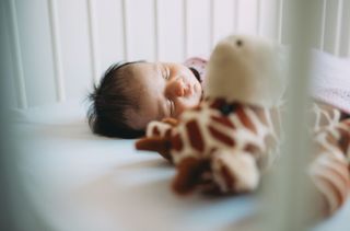 baby in cot with toys