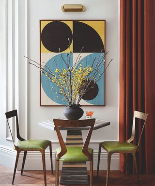 dining table with three chairs and abstract artwork and vase of foliage