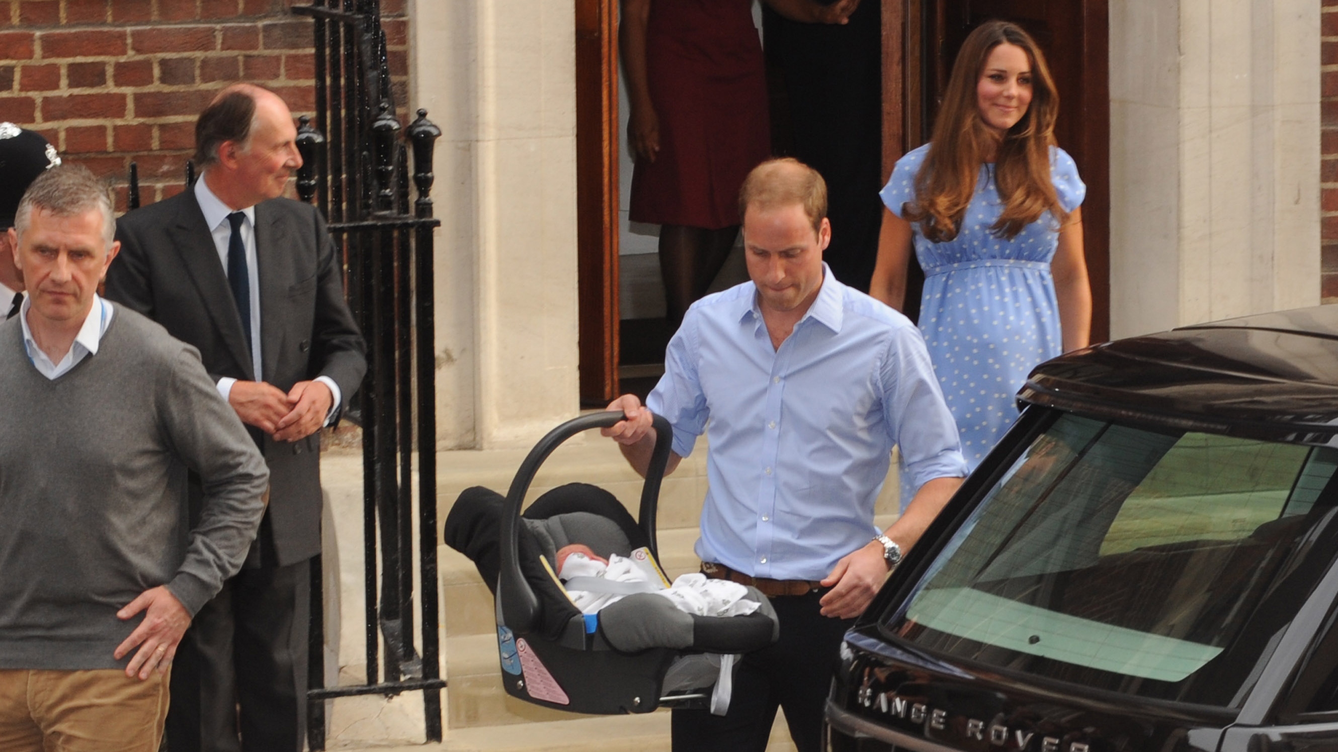 Catherine, Princess of Wales watches as Prince William carries Prince George in his car seat at St Mary's Hospital on July 23, 2013