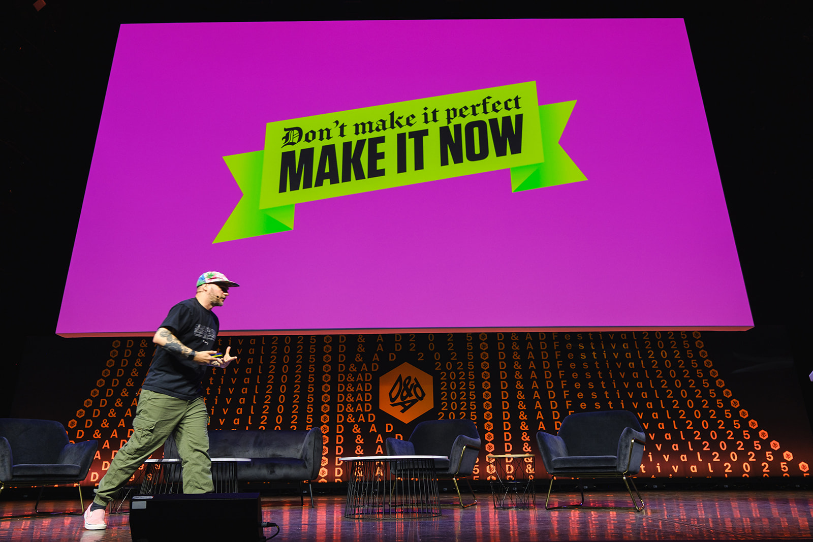 Gavin Strange on stage at D&AD Festival with bright colours behind him and text that says don't make it perfect make it now