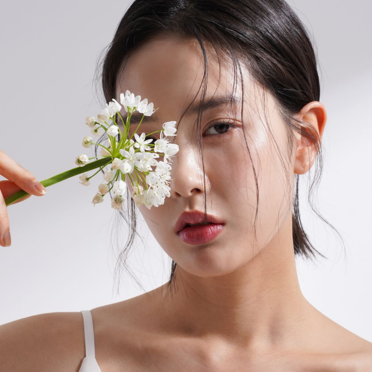 An image featuring an Asian woman holding a flower