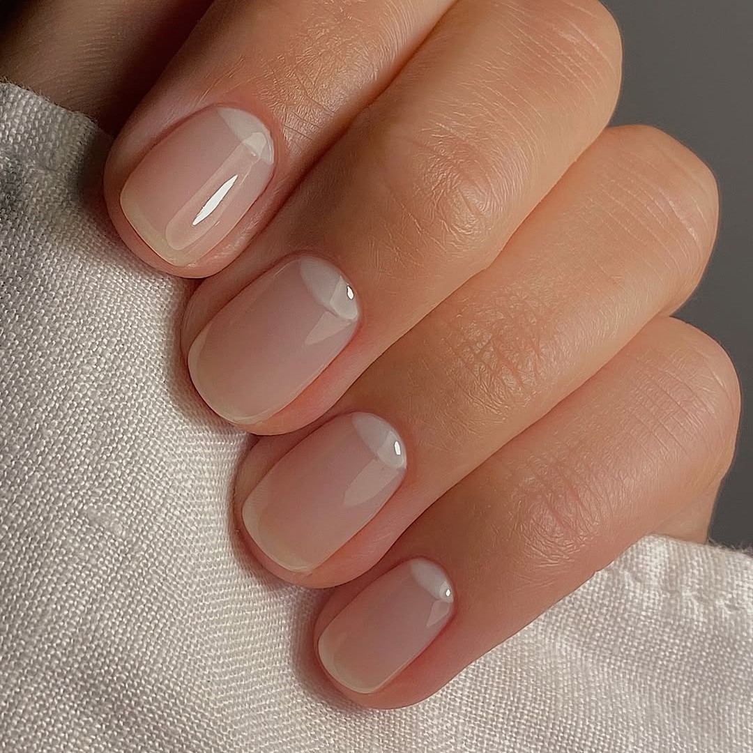 A hand with a reverse French-tipped manicure.