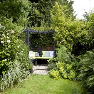 Pretty garden, grass lawn, black arbour frame, bench seating, cushions