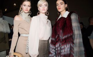 Model wears a sik neck scarf and pink dress, another is in a pink blouse and tailored trousers, another wears a fur coat.