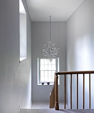 staircase with white walls and sculptural chandelier