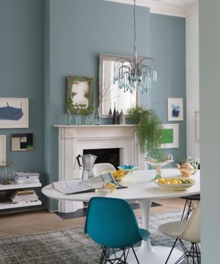 dining room with light blue wall, white fireplace, white dining table with blue and white chairs