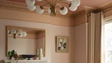 Close-up image of a wall and ceiling where three tonal gradient colors are used. There is crown molding around the ceiling and a mirror hanging on the wall.