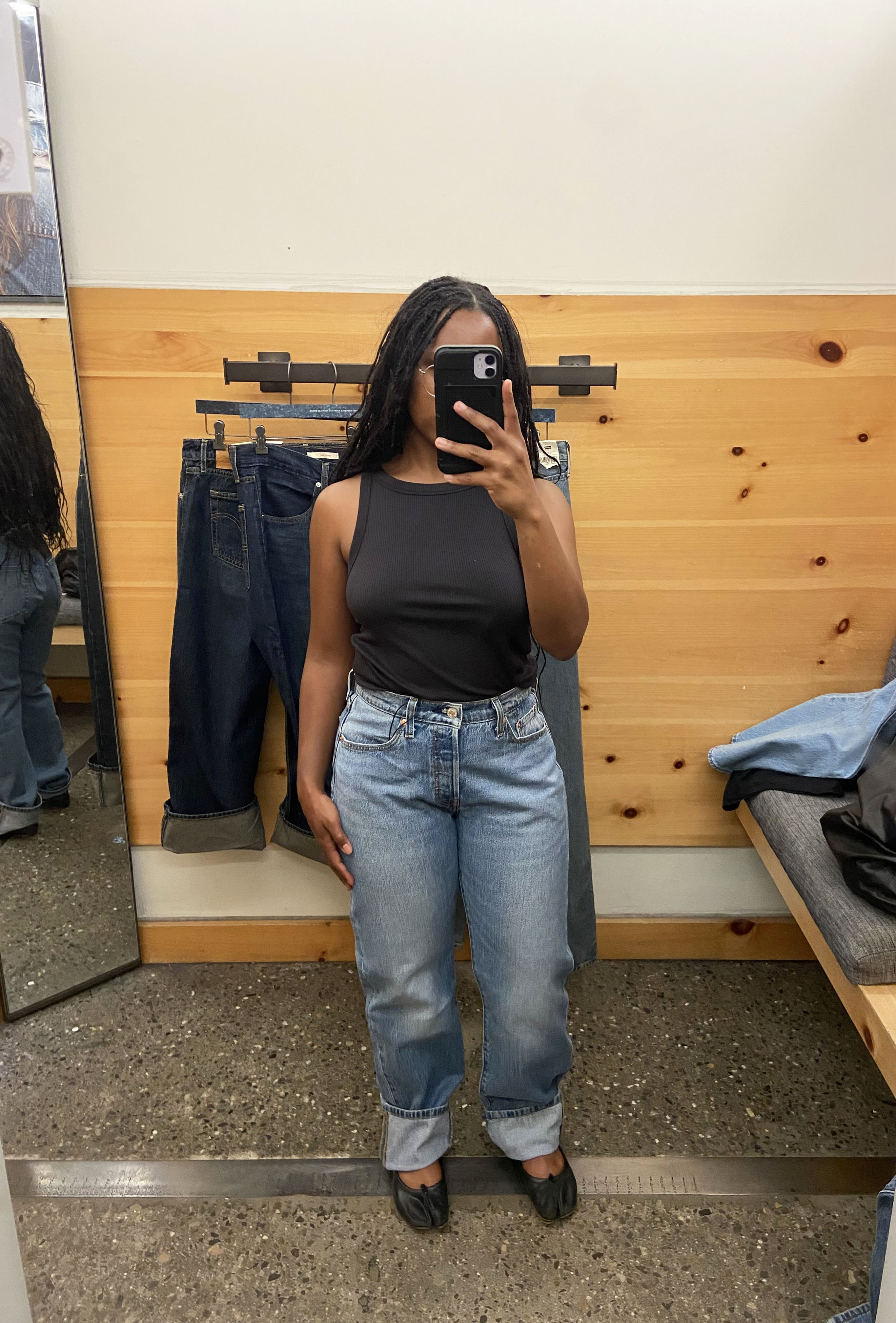 a woman wearing light wash jeans and a black tank top