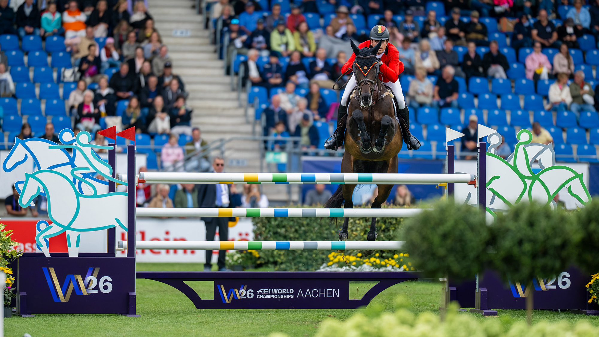 Nicola Phillippaerts and Katanga Van Het Dingeshof clear a white fence with coloured stripes during the showjumping World Championships in Aachen