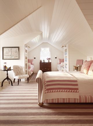 A pink bedroom with a pink-and-white striped quilt on the bed