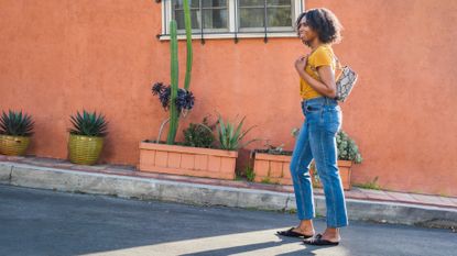 A woman walks up a street with an incline.