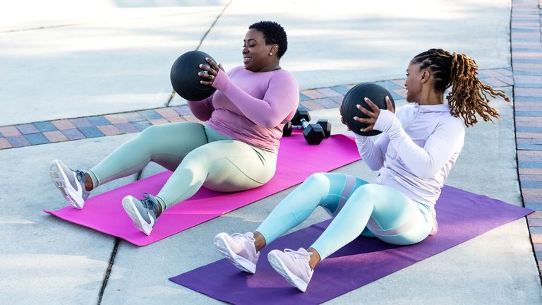 Women enjoy an outdoor workout using medicine balls