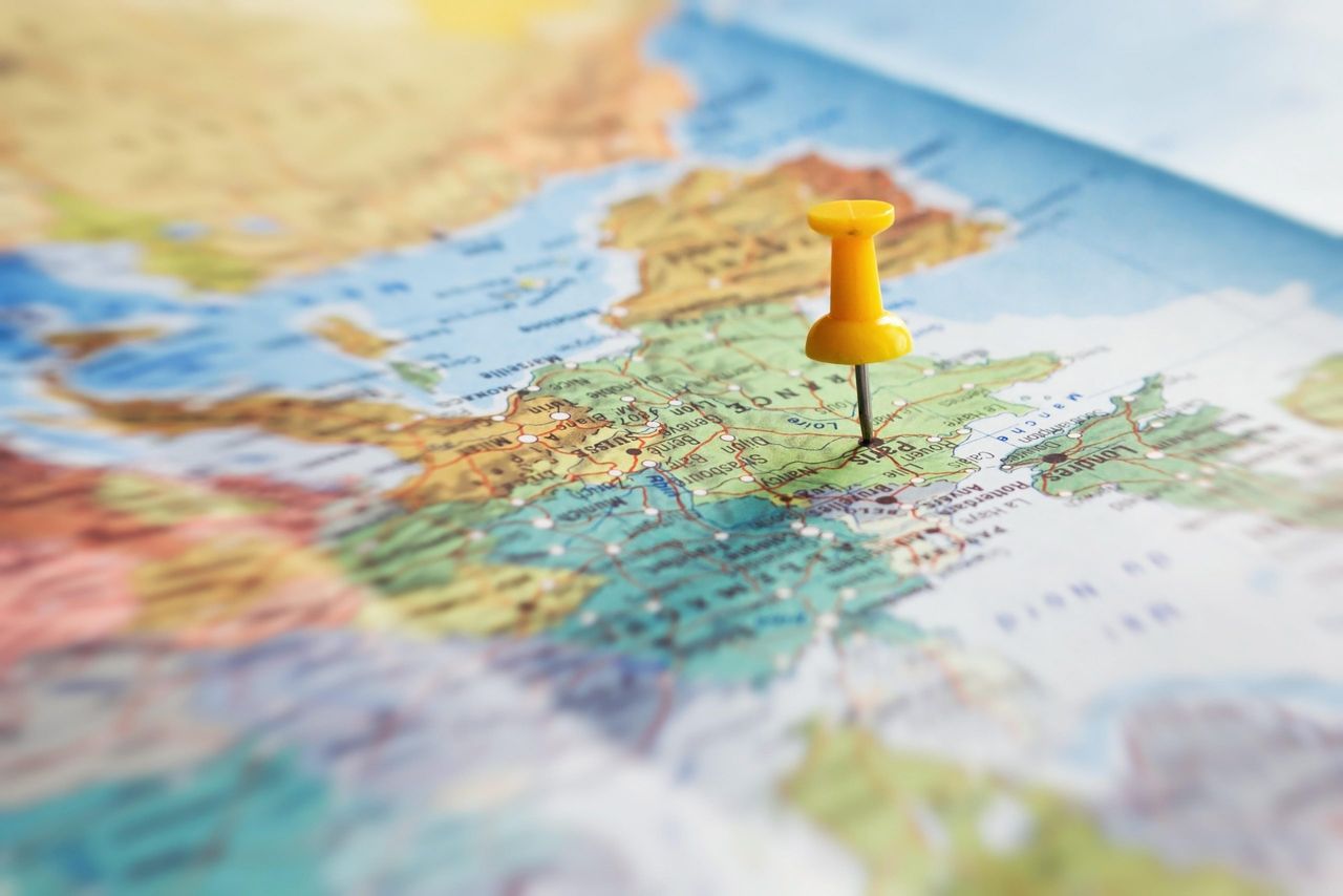 A close up of a world map with a yellow pin in the country France