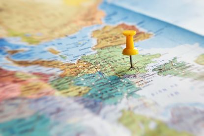 A close up of a world map with a yellow pin in the country France