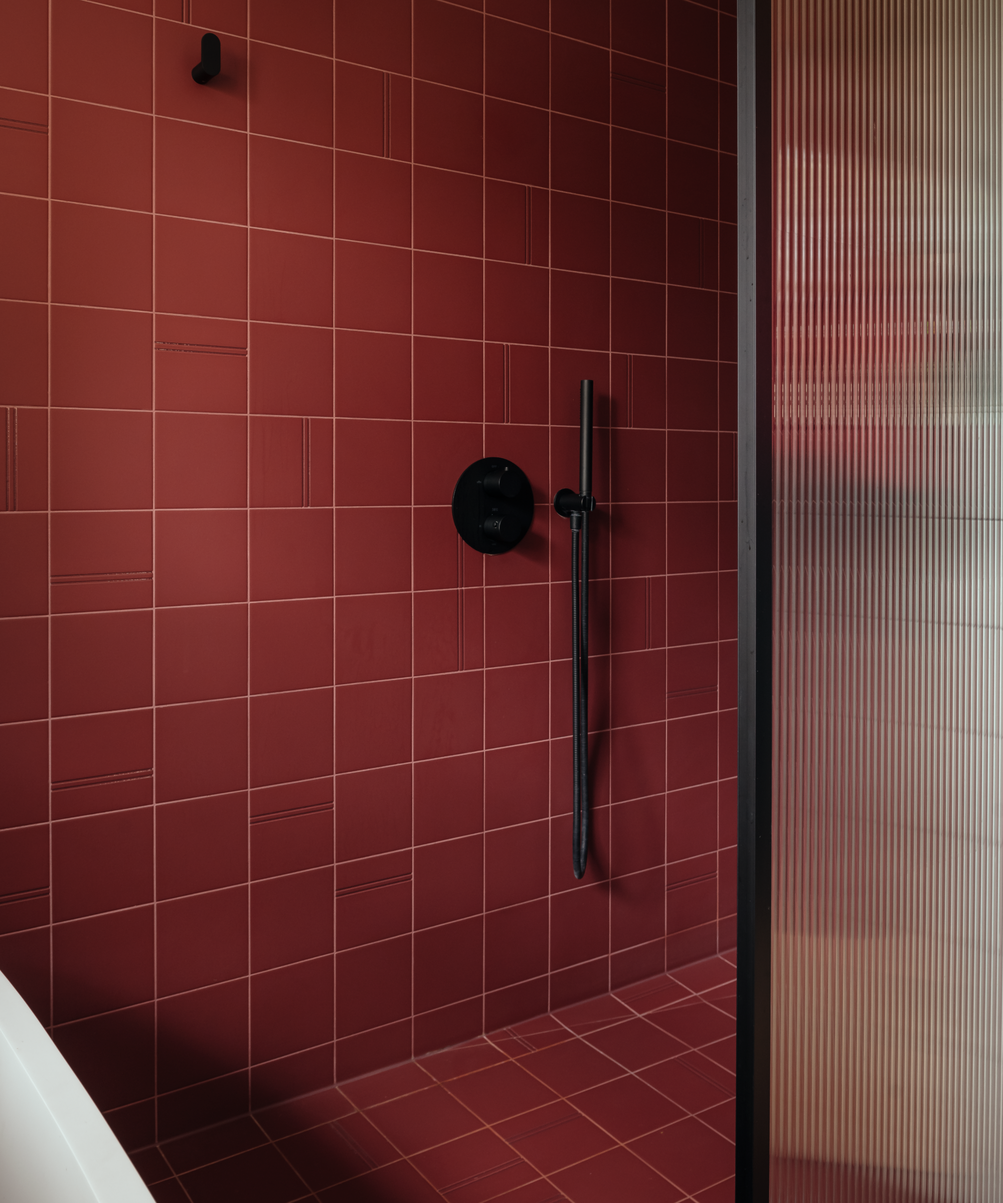 Shower with burgundy square tiles and black accents